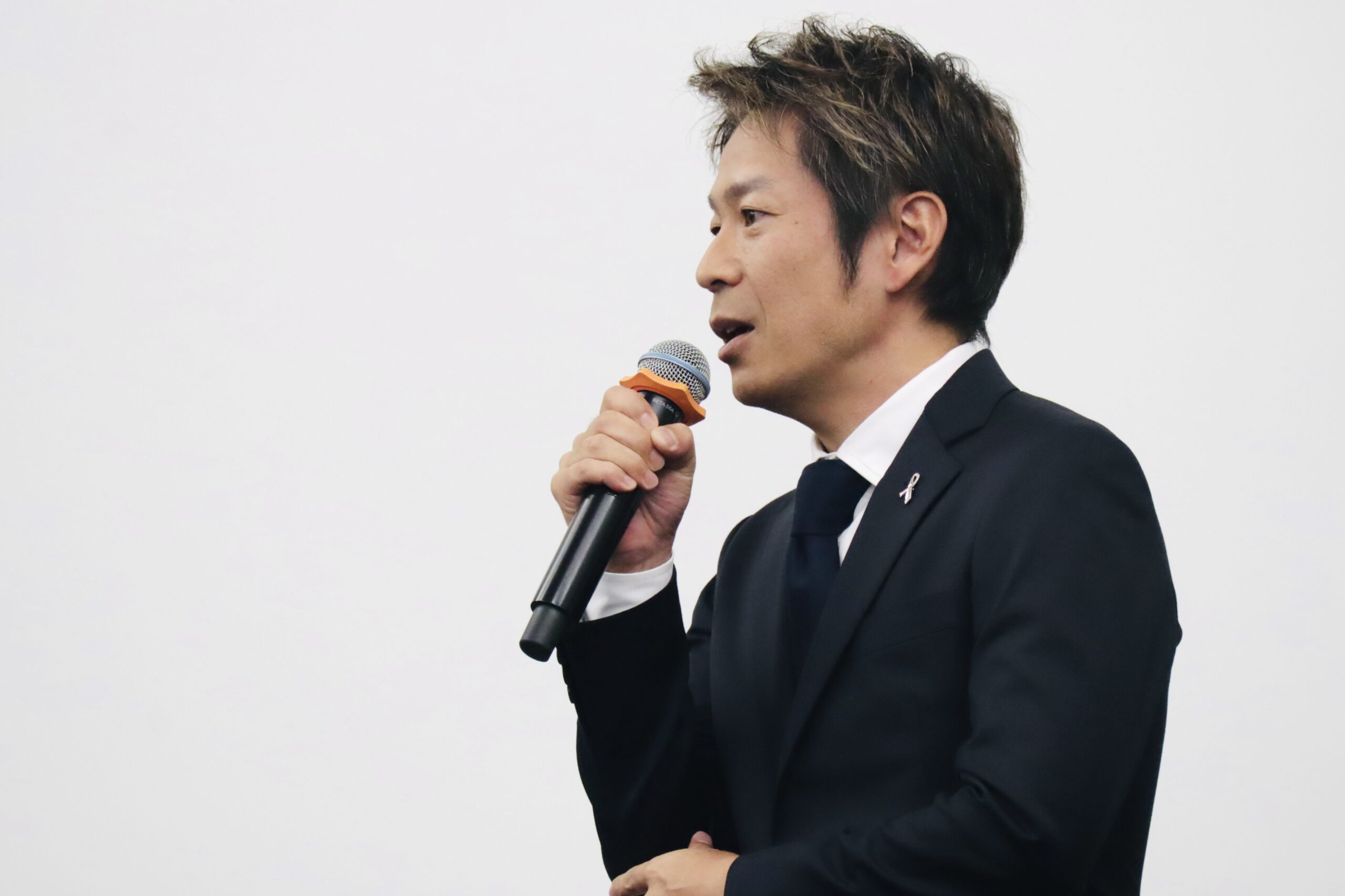 洛和会ヘルスケアシステム合同内定式でマイクを持ち講演する清水健