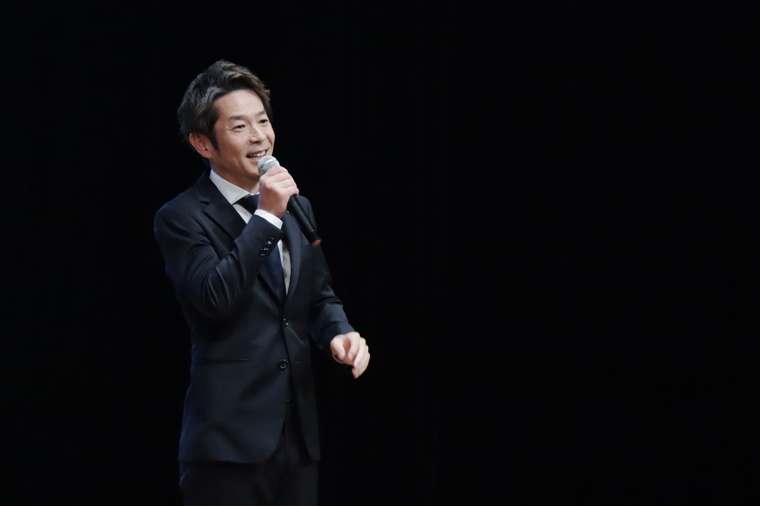 日本小児臨床アレルギー学会学術大会で特別講演を行う清水健。講演テーマ「今を生きる － 言葉の力と日常の尊さ －」について語る様子。