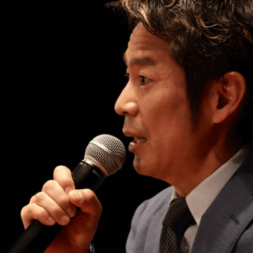 講演会でマイクを手に話すフリーアナウンサー清水健の横顔