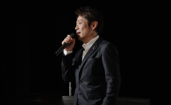 講演会で横顔の姿で語りかけるフリーアナウンサー清水健