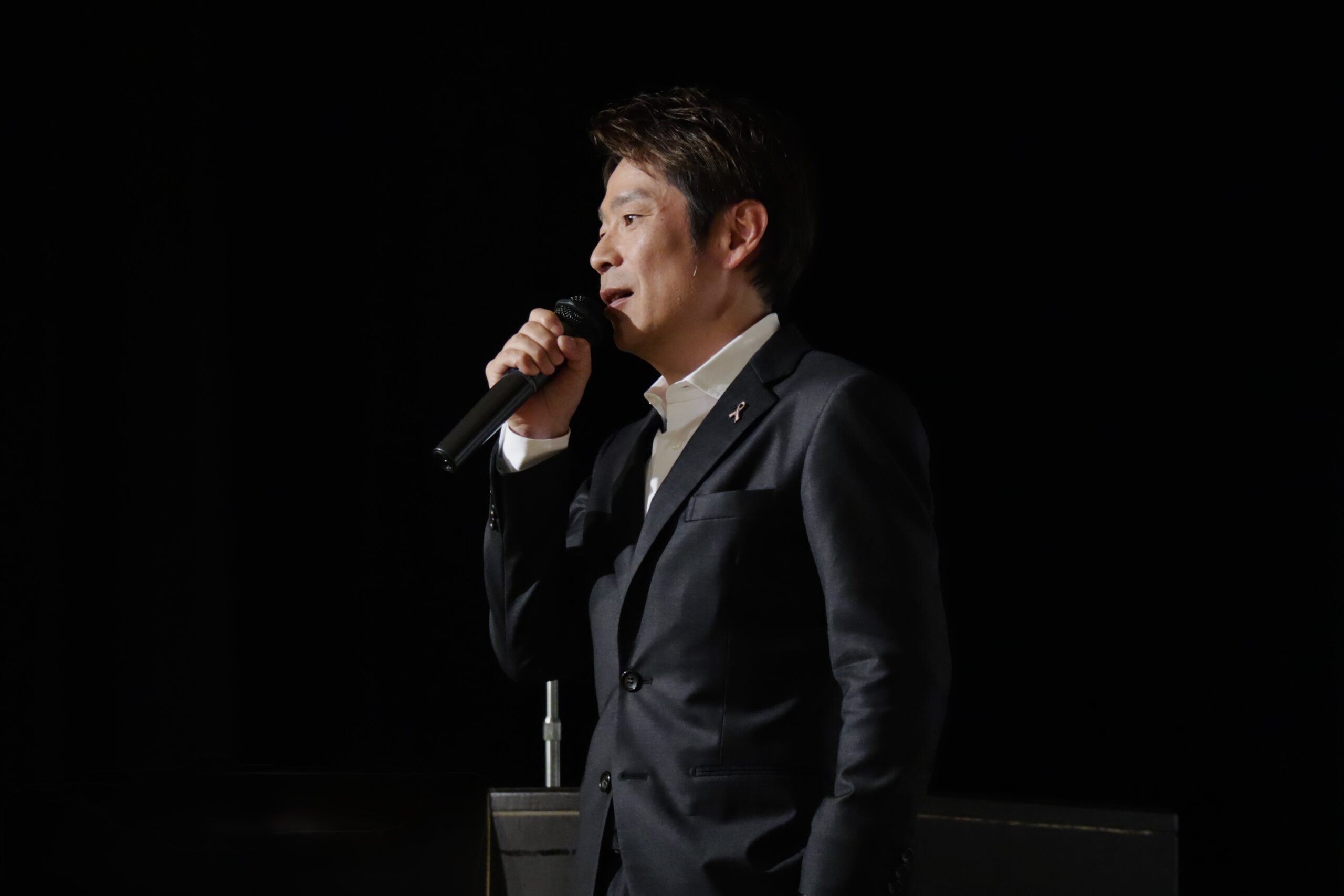 講演会で横顔の姿で語りかけるフリーアナウンサー清水健